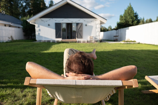 Anonymous man relaxing in yard of suburban house