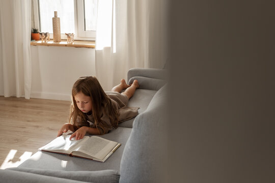 Kid resting on sofa with book