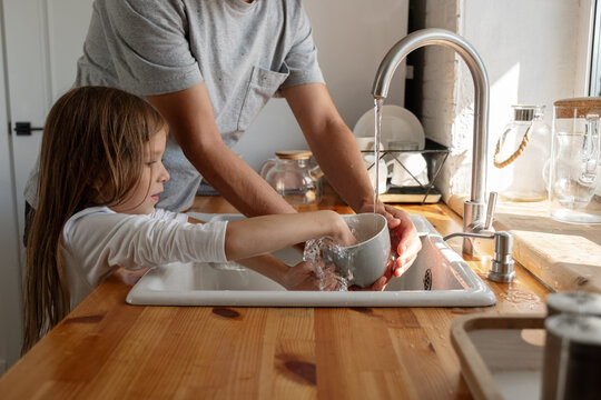 Kid helping father to wash dishes