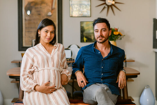 Pregnant couple sitting at home portrait