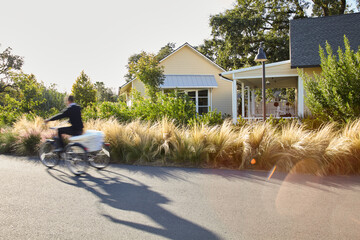 Housekeeping employee riding bike at resort with towels