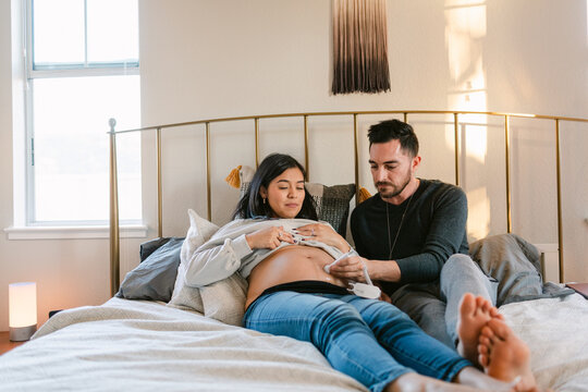 Expectant couple listening to fetal heartbeat in bed