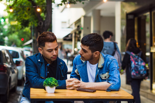 Gay couple holding hands and talking seriously