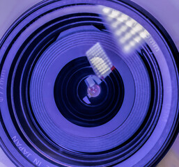 Macro looking into front of a DSLR lens showing LED light reflections in lens elements