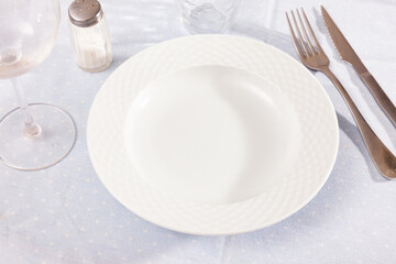 Empty ceramic plate with silverware on table. Table setting, nothing served.
