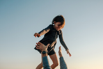Young girl high above father's arms