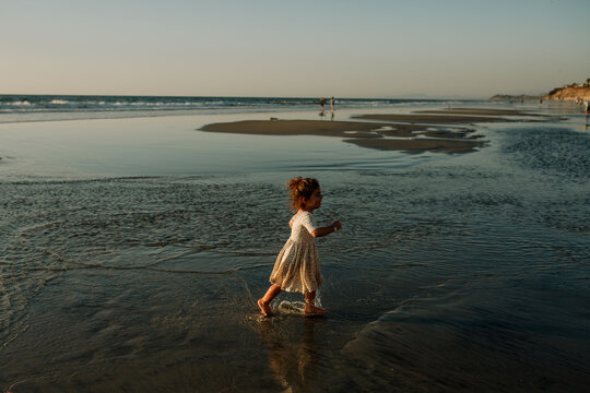 Girl in dress wading in ocean at sunset