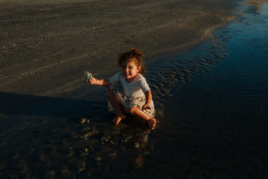 Girl sitting in ocean holding seashell