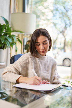 Focused woman writing during psychotherapy session
