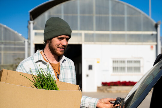 portrait of Man placing shopping box into car trunk