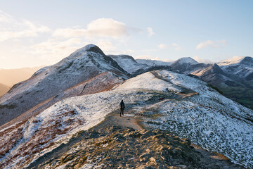 Walker in the snow at sunrise on Cat Bells