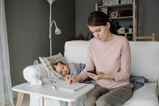 Mother searching treatment on smartphone near sick child