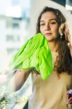 Woman cleaning window on sunny day