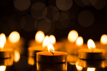 Candles in the dark with reflection and shallow depth of field, with lights in the background