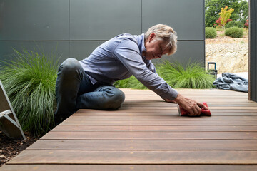 Homeowner sanding timber deck before painting