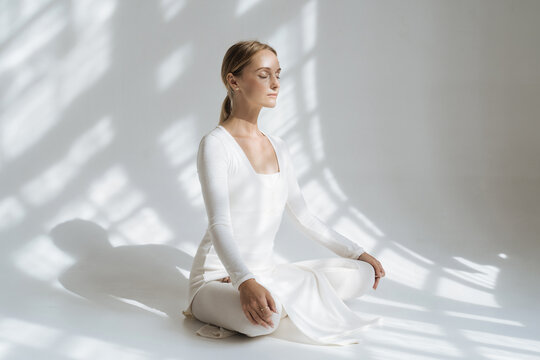 Woman doing yoga in white studio