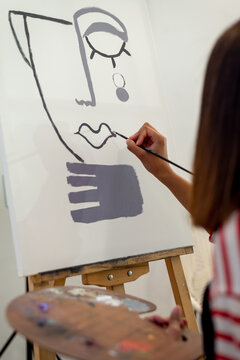 Black woman painting on canvas in workshop
