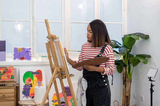 Woman painting on easel in workshop