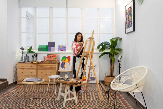 Woman painting on easel in workshop