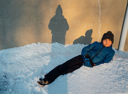 Boy lounging in a pile of snow. 