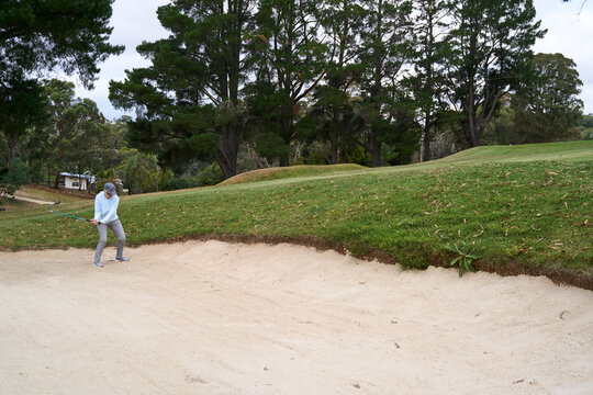 Golfer hitting ball out of sand bunker