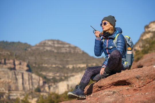Female hiker using on walkie talkie on cliff slope