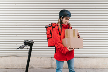 Woman with cardboard boxes standing near e scooter