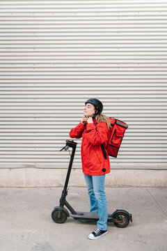 Delivery woman fastening helmet before riding scooter