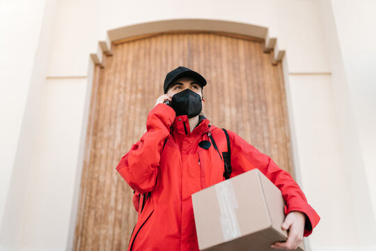 Serious delivery woman with parcel having phone call