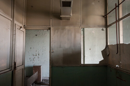 Interior of an abandoned office building, in a dirty and damaged room, with an broken window and desk remaining after the closure and the bankruptcy of the business. .....