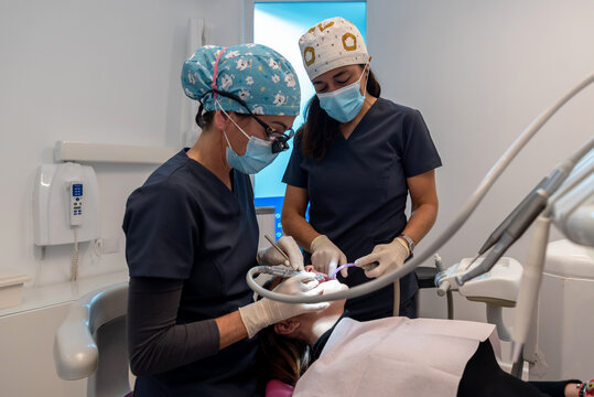 Professional dentists treating teeth of female patient