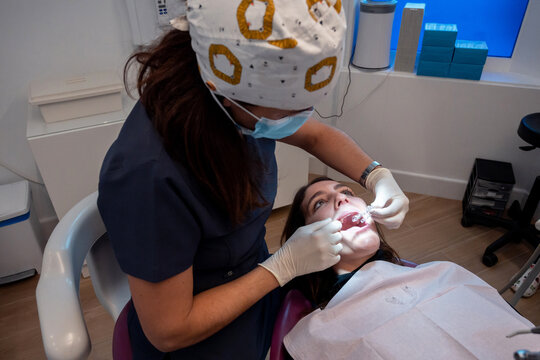 Female dentist putting invisible orthodontics to client 