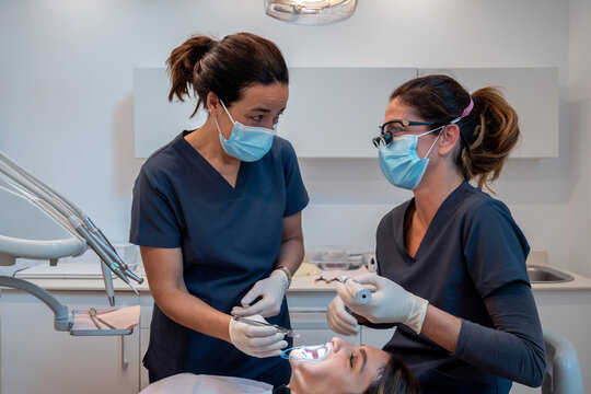 Professional dentists treating teeth of female patient