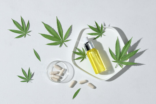 Hemp oil serum in glass dropper bottle on cannabis leaves. 