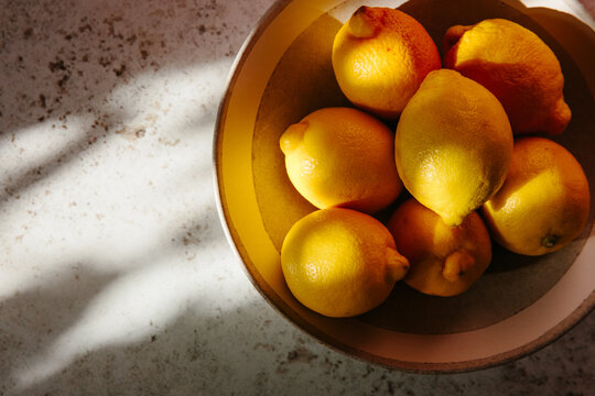 A bowl of lemons in dappled light.