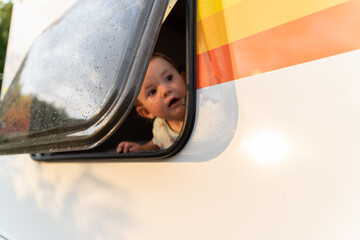 Curious happy baby girl looking out the window