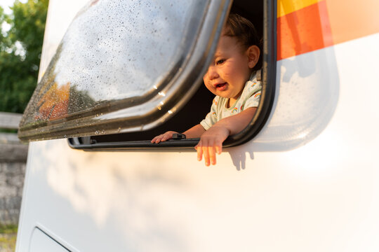 Curious happy baby girl looking out the window