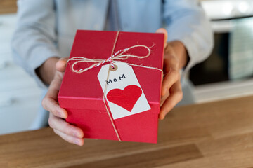 Man showing present for his mother at camera