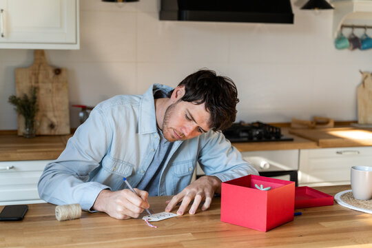 Man writing gift card in modern kitchen