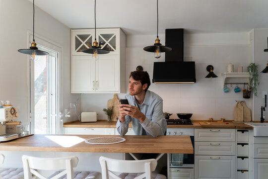 Portrait of happy confident man with phone at home