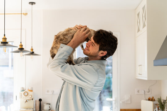 Portrait of happy man hugging cat at home