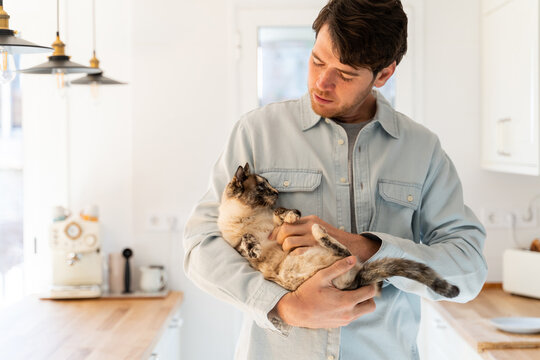 Portrait of happy man hugging cat at home