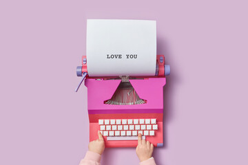 Kid typing text love you on colorful retro typewriter