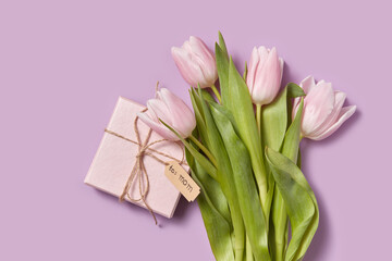 Bouquet of tulips and gift box for mom on pink background