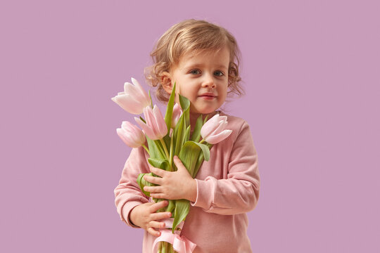 Pretty kid holding bouquet of tulips in studio