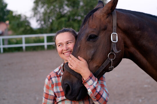 portrait of a happy village woman hugging a horse muzzle 