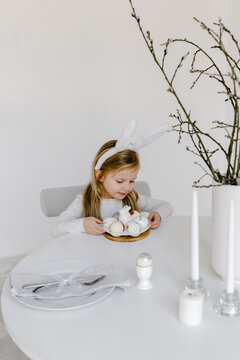 Child sitting with plate of Easter eggs at table 