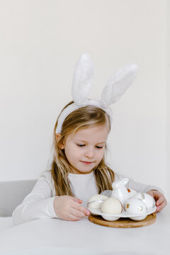 Child in bunny ears with decorated Easter eggs