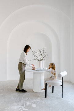 Woman with kid putting Easter eggs on table
