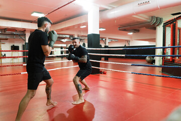 Sportsmen boxing on ring in gym
